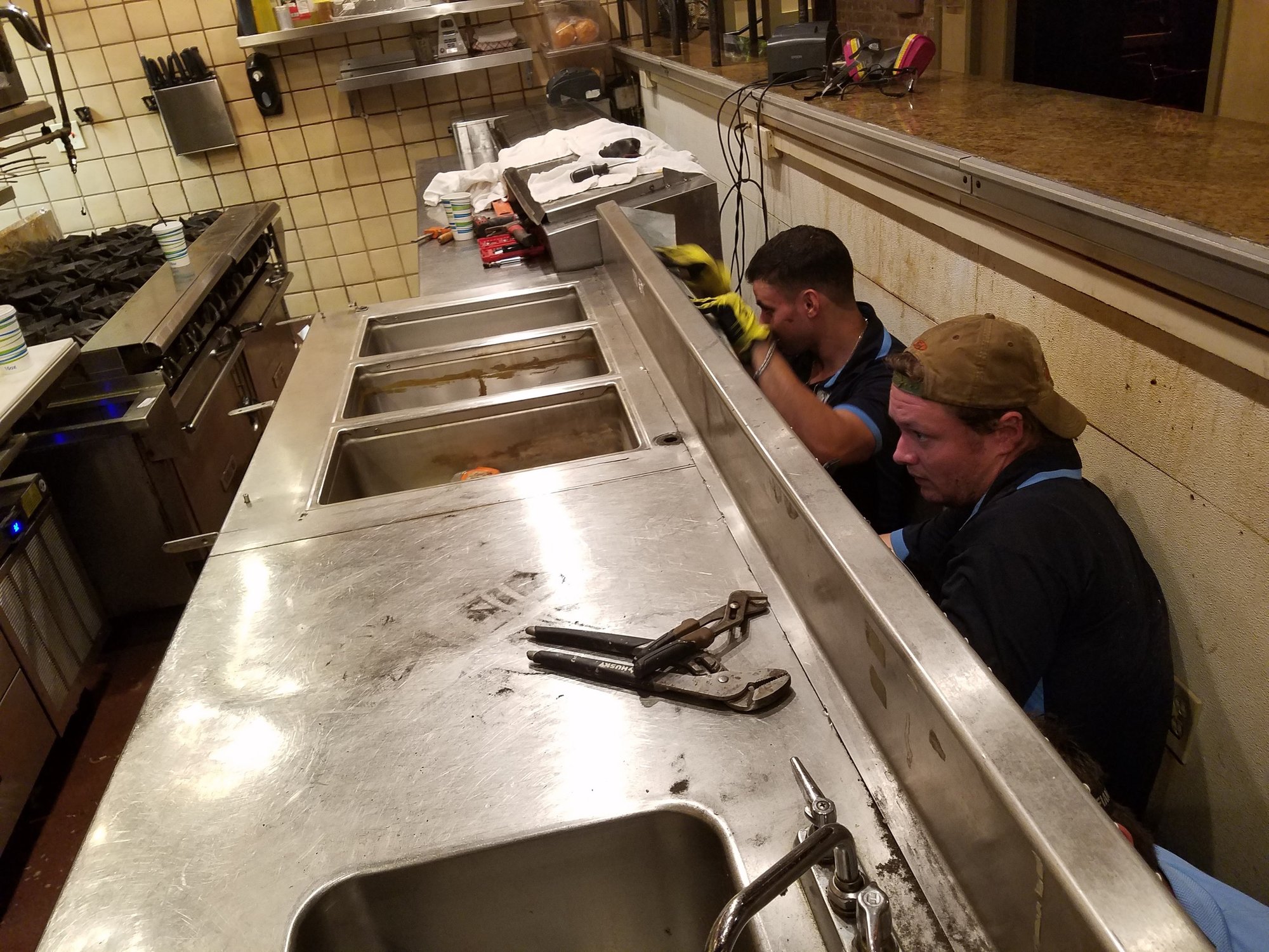 Two Pro Gasket Group technicians working at a stainless commercial prep line